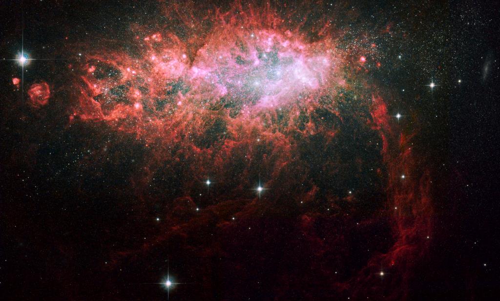 A bright red galaxy shines near the top of the image in shades of pink and white.