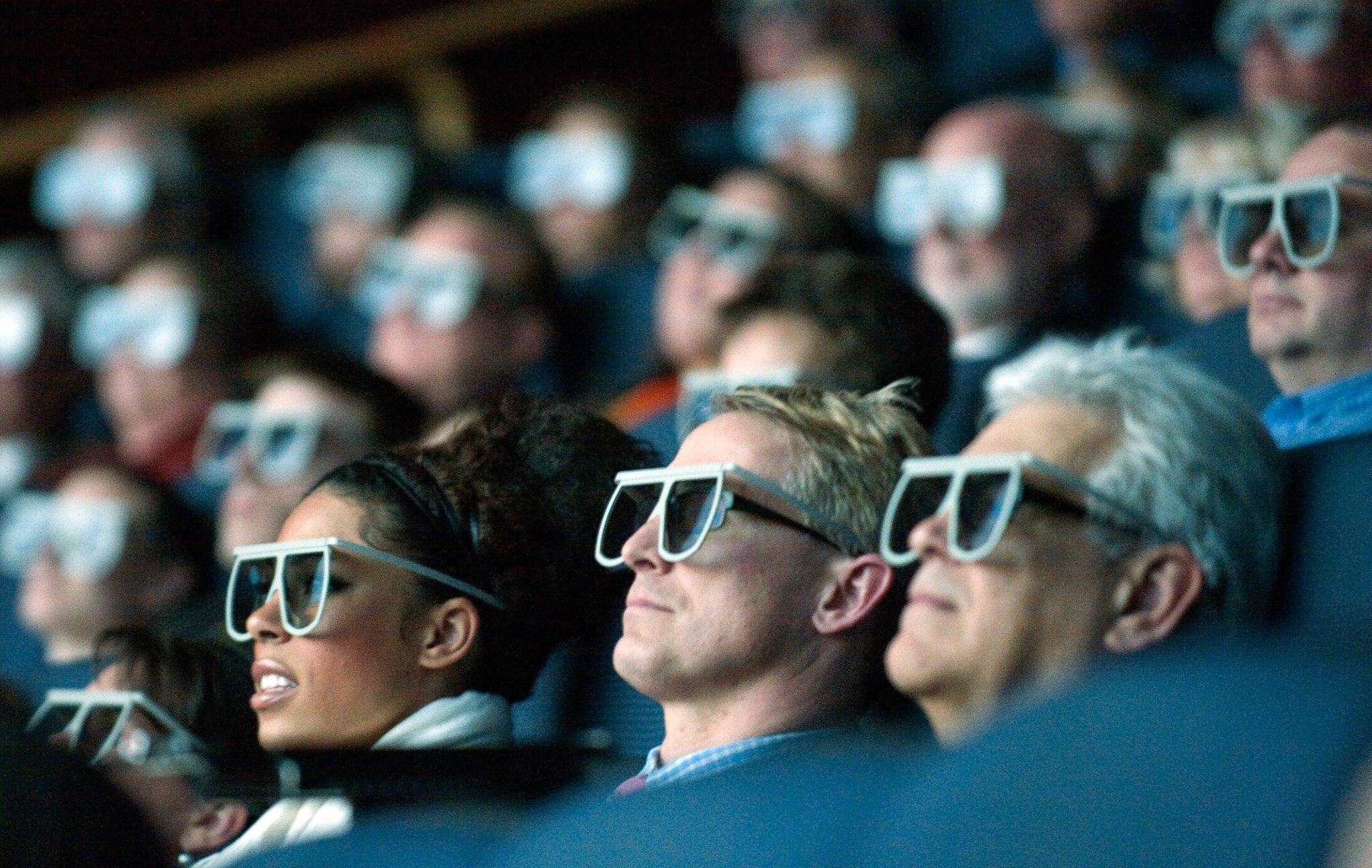 An audience of movie watchers wearing 3D glasses.