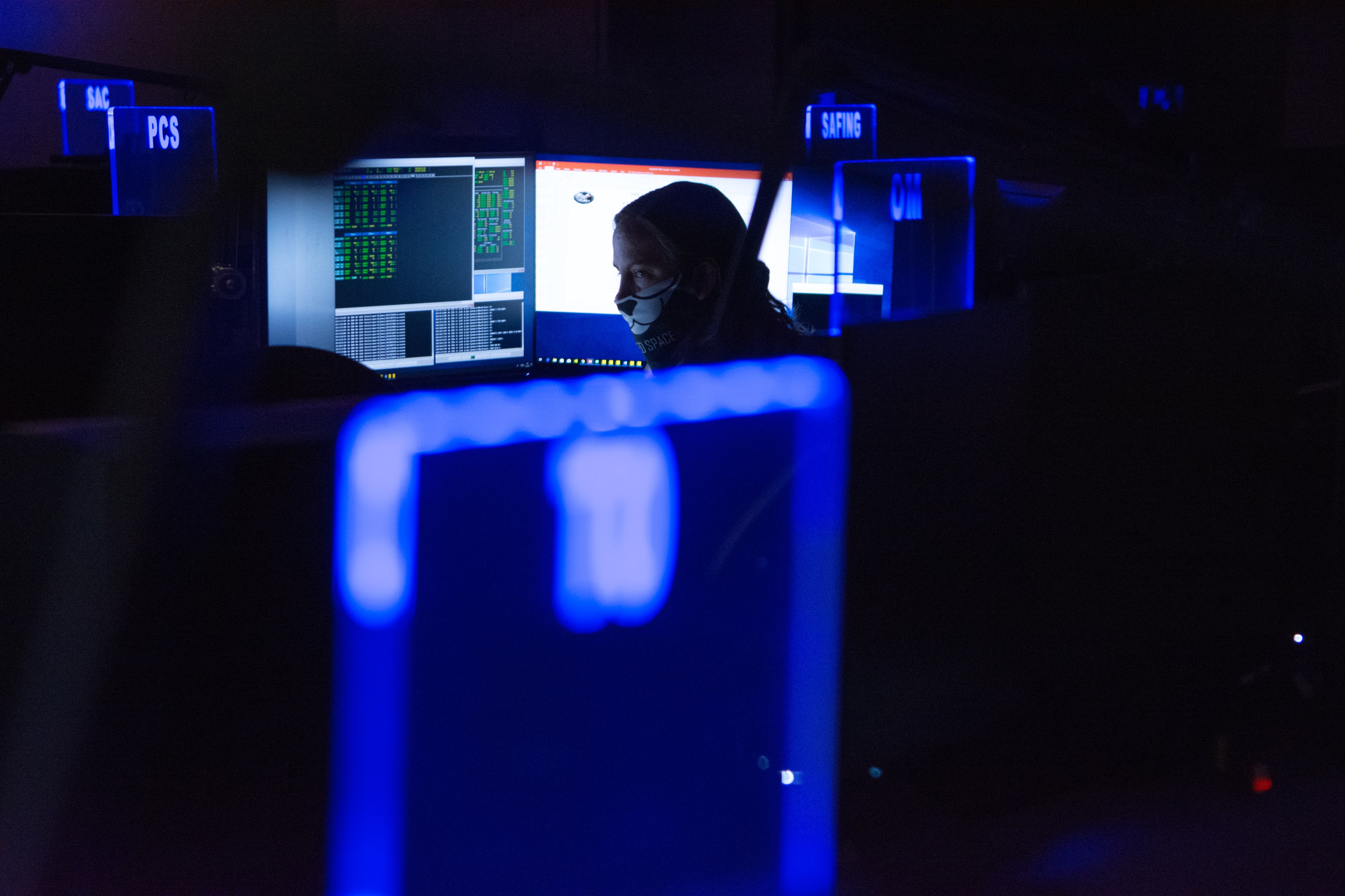 A woman studies the data on a monitor in a low lit Hubble operations room.