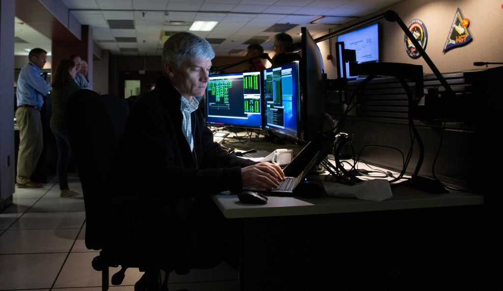 A man types on a laptop in the Hubble control center