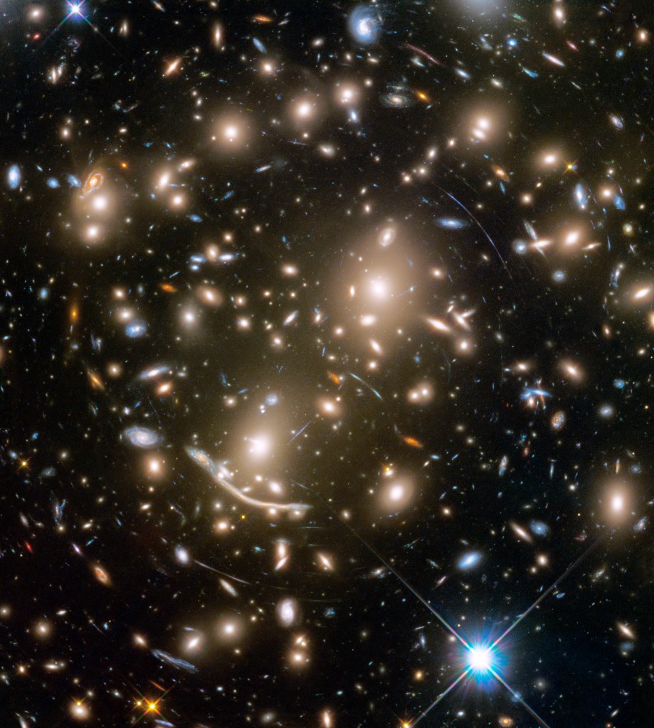 Large grouping of galaxies warped around what appears to be a giant lens. Each galaxy appears as a glob of light.