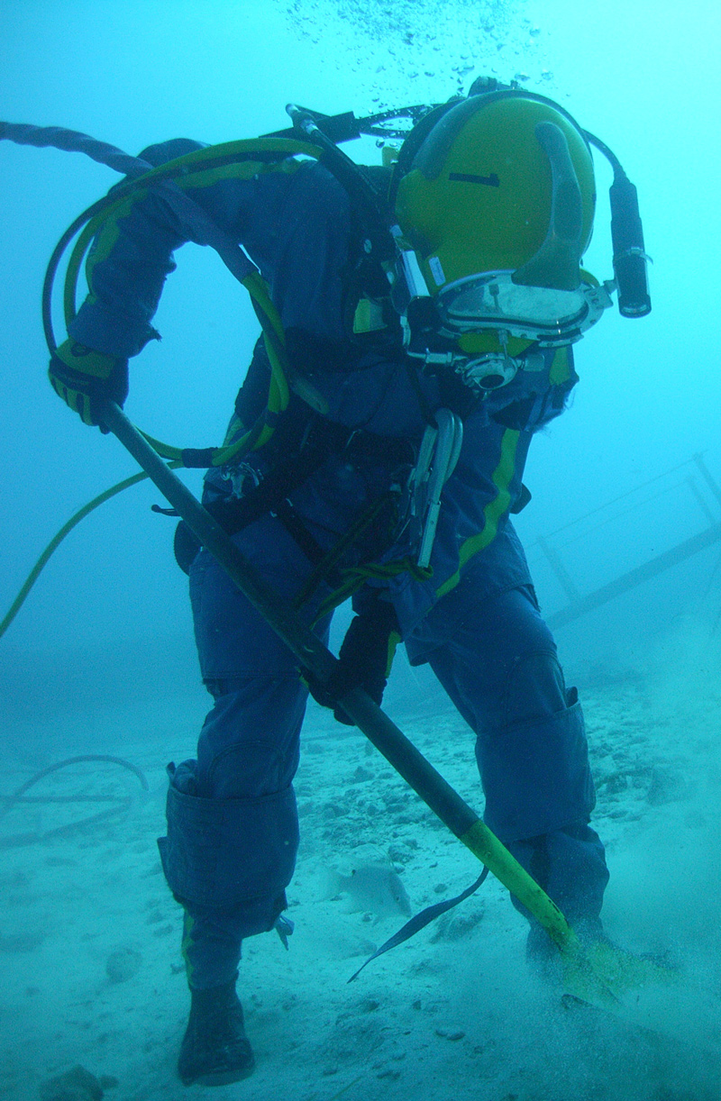 A SCUBA diver practices sample collection underwater, on the seafloor.