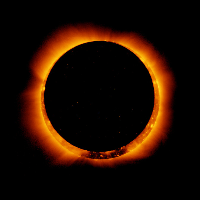A black circle is in the middle it. Around it, an orange and red Sun peeks through. Streams of orange light pour off the edge of the Sun on a black background.