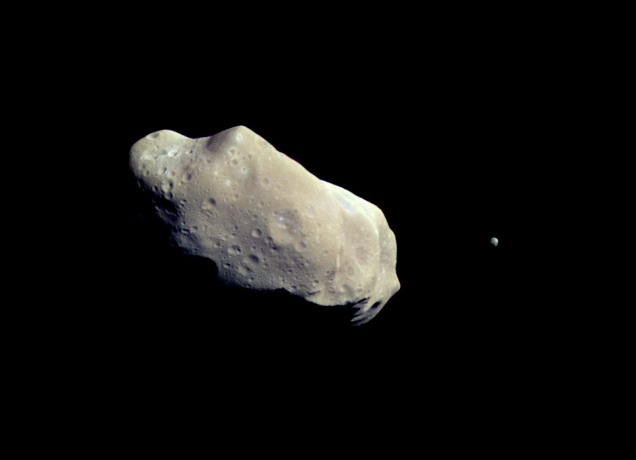 This image from the Galileo spacecraft shows a tiny moon in orbit around a huge asteroid.