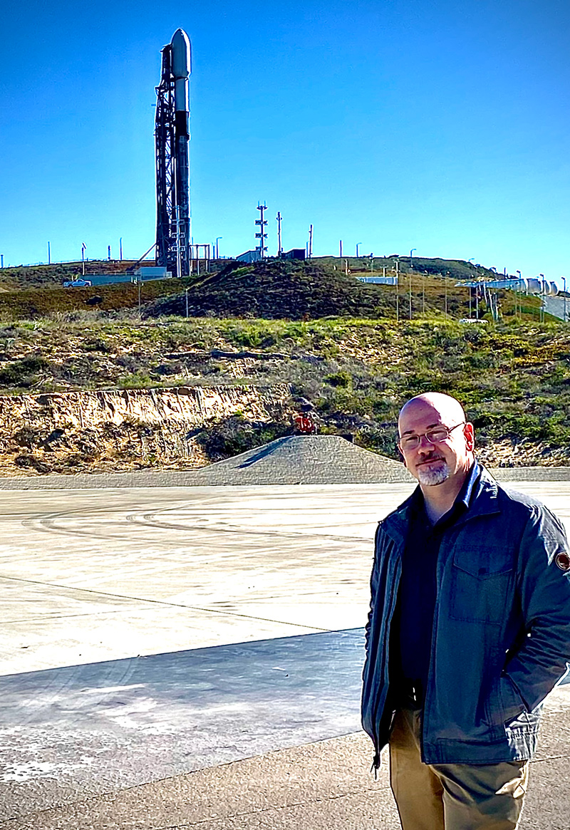 Eric Ianson stands, hands in pockets, in front of a rocket on the launch pad.