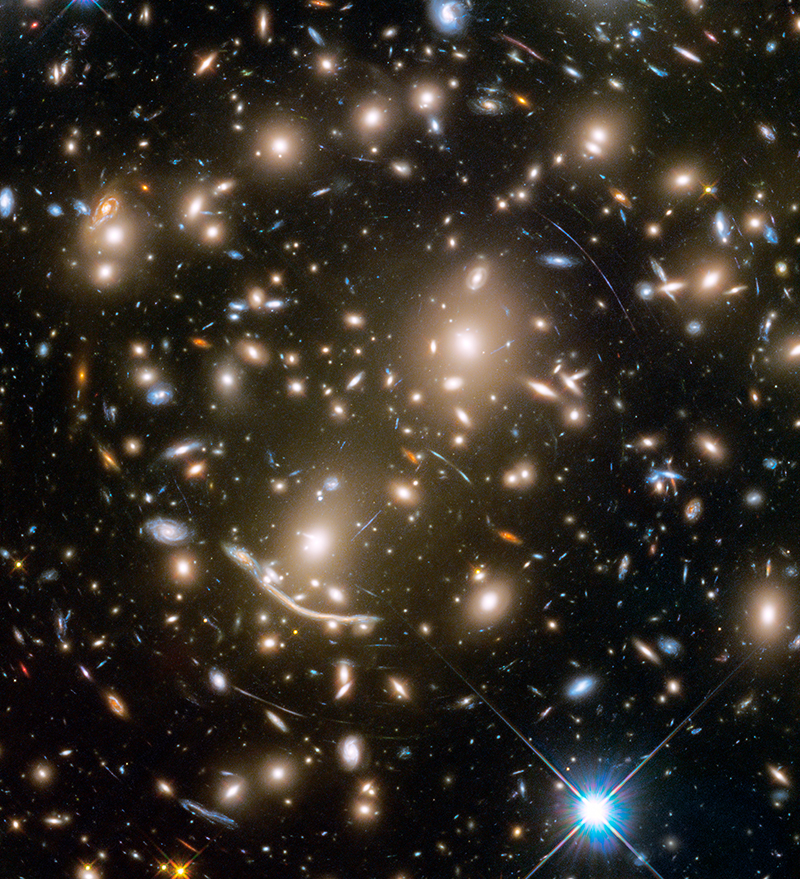 Large grouping of galaxies warped around what appears to be a giant lens. Each galaxy appears as a glob of light.