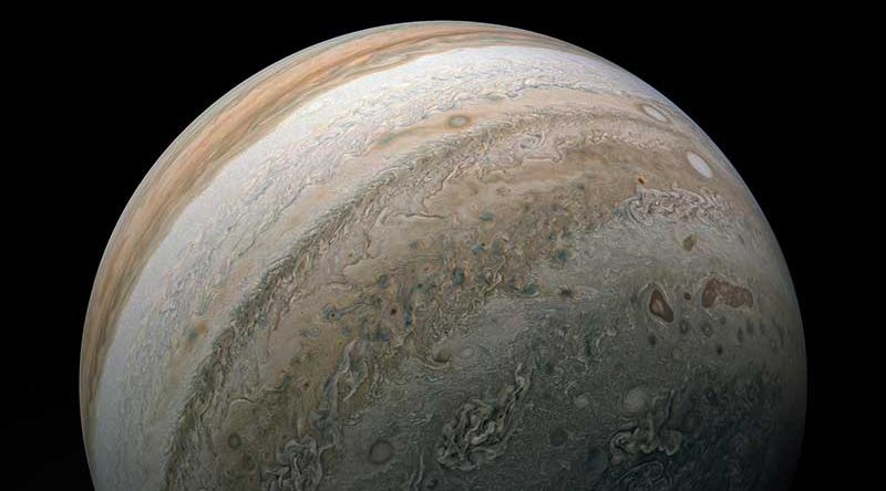 Three-quarters of planet Jupiter is visible, with alternating swirling bands of brown and white present.