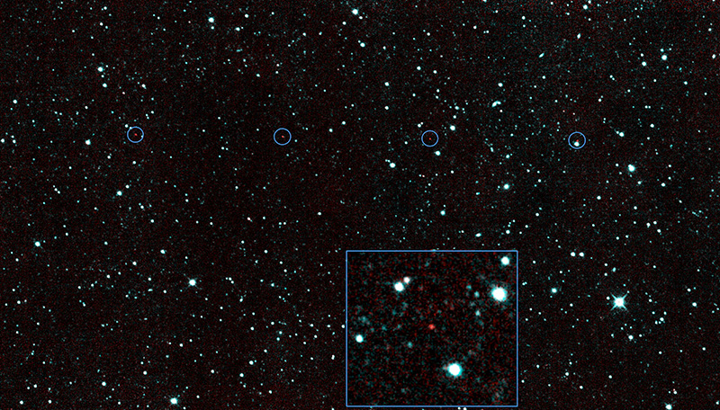 The image shows a star field in space, hundreds of scattered dots of greenish white, of varying sizes and brightnesses, against a black background. Lined up horizontally in the upper third of the image are six evenly spaced small red dots, with blue circles dran around each to set them off. A small, blue-lined box at the bottom of the image shows a magnified view of one of the red dots, and the stars surrounding it.