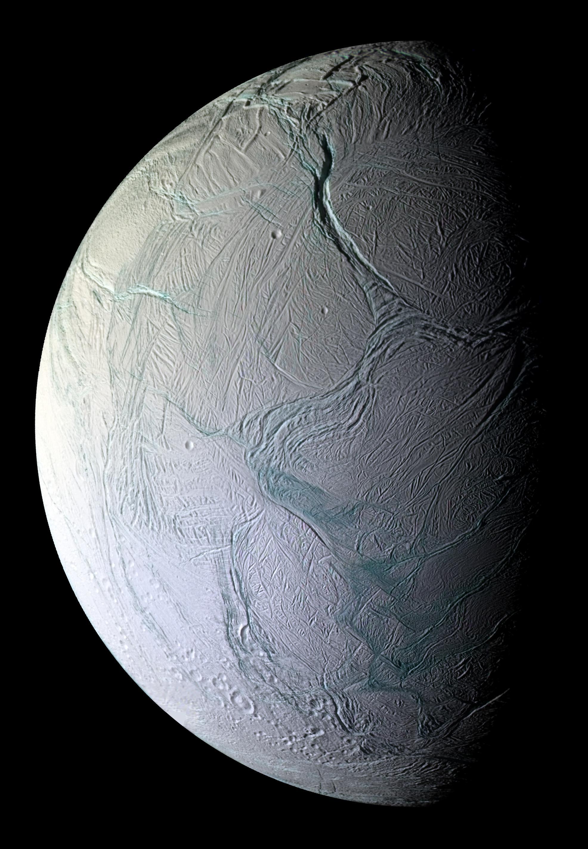 The icy white surface of a moon in space is completely covered in wrinkles, folds, and fractures, some appearing bluish in color.