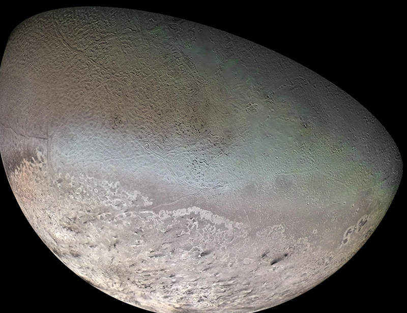 A closeup view of one hemisphere of Triton shows frosty, rippling terrain on a light brown surface. There is a difference in the appearance of the terrain from top to bottom, with the lower part appearing brighter.