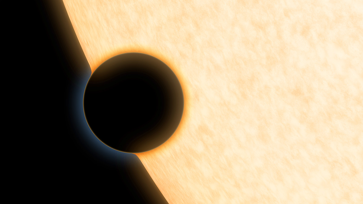 The silhouette of a planet is seen agains the surface of its star. A hazy envelope of atmosphere can be seen surrounding the planet.