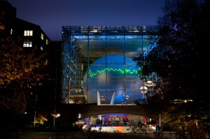 A jagged, EKG-like spectra line from the Hubble Space Telescope is projected onto a large sphere seen through a windowed wall at Hayden Planetarium