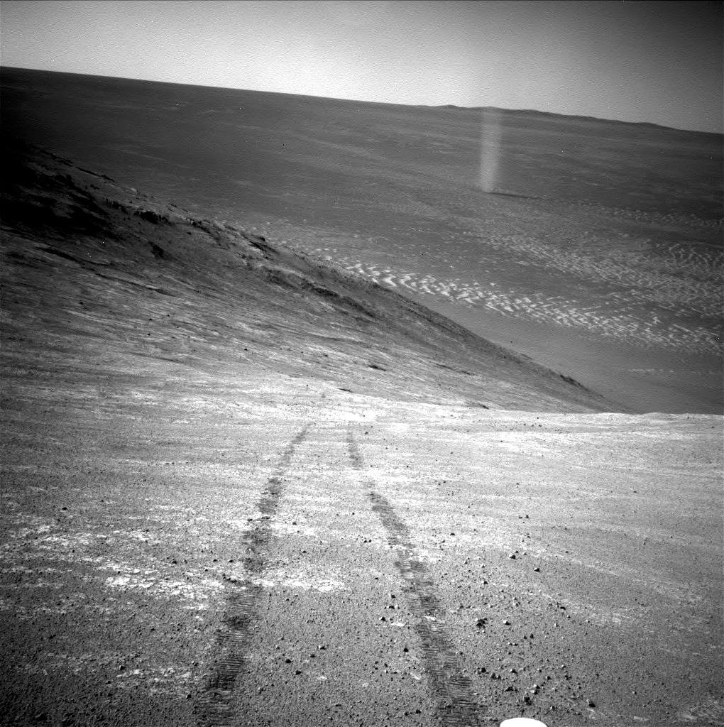rover tracks on a hillside with a dust devil seen in the distance