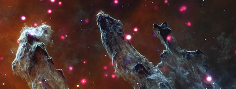 The Eagle Nebula, also called M16, and often referred to as the "Pillars of Creation." Here, tall columns of gray gas and dust emerge from the bottom edge of the image, stretching toward our upper right. Backed by dark orange mist, the cloudy gray columns are surrounded by dozens of soft, glowing, pink and purple dots; massive stars emitting enormous amounts of X-rays. The shapes, hints of movement, and colors in this composite rendering create a dream-like image. The misty orange background suggests a dusky sky, and the glowing pink and purple stars resemble fireflies. Churning with turbulent gas and dust, the columns lean to our right with small offshoots pointing in the same direction. These details evoke an image of yearning cloud creatures at dusk, pointing at something just out of frame.