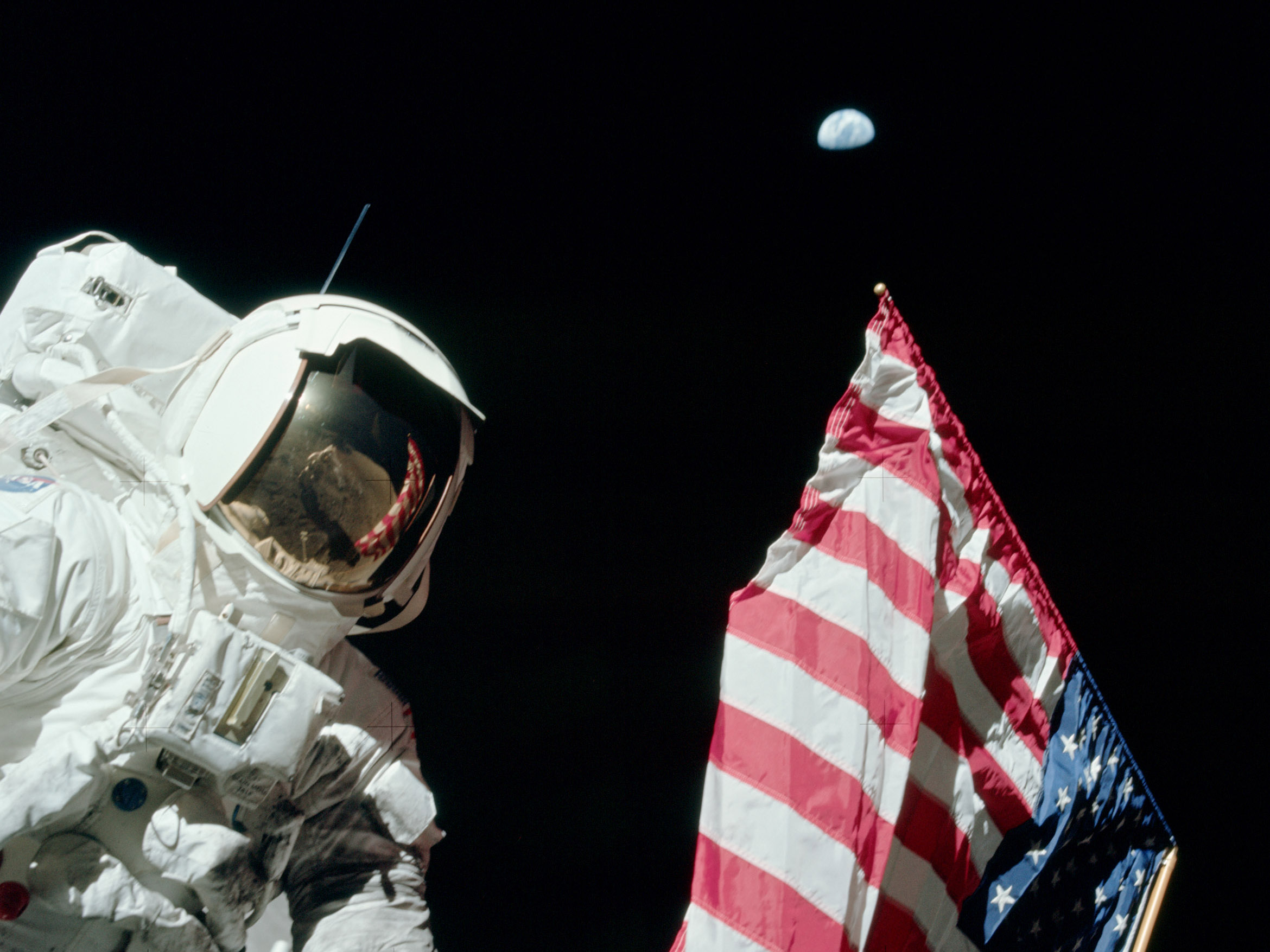 Apollo 17 astronaut Jack Schmitt with the U.S. flag, its pole pointing to Earth in the sky.