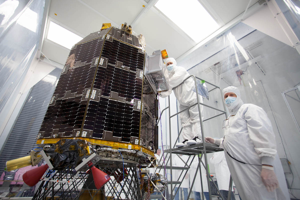 Engineers, fully covered in white scrubs and masks, prepare NASA's Lunar Atmosphere and Dust Environment Explorer (LADEE) spacecraft for acoustic environmental testing.