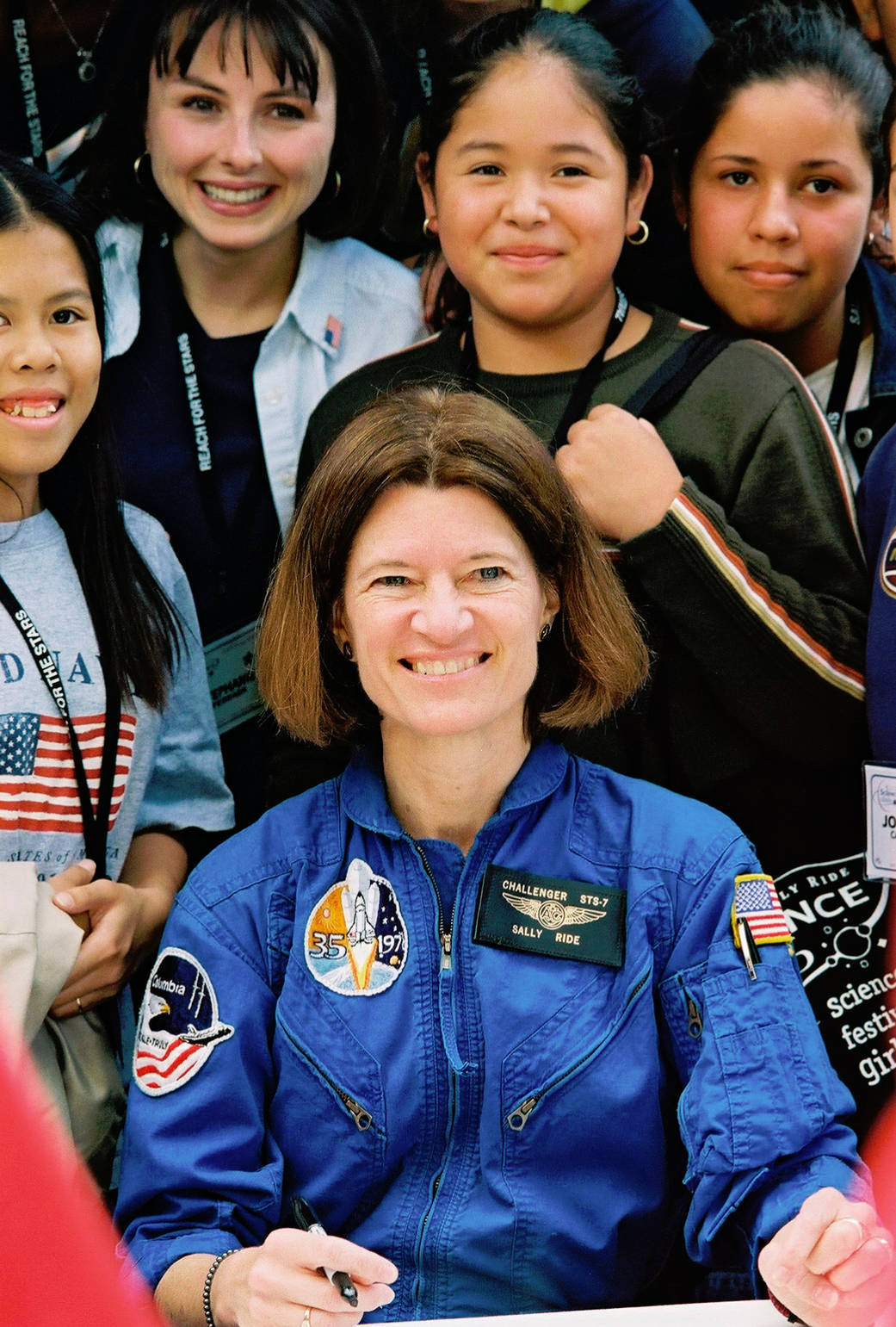 Color image of woman astronaut surrounded by kids.
