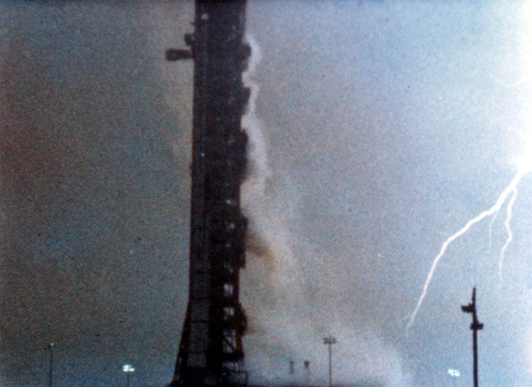 Mobile launch tower under a stormy sky with a lightning bolt. The Saturn 5 rocket for the Apollo 12 mission was struck by lightning - twice.