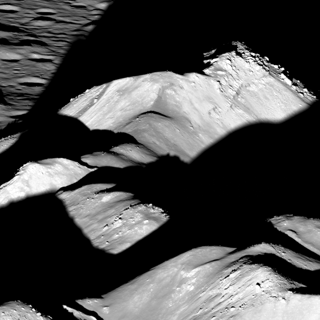 Oblique view of tall, rugged lunar mountains. Bright sunlight casts dramatic shadows between the peaks.
