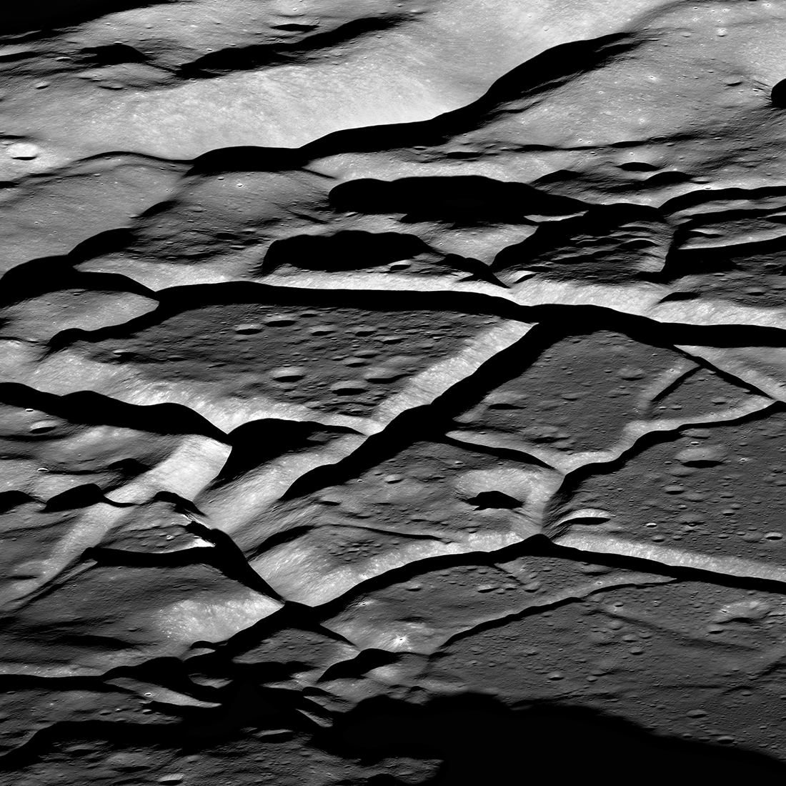 Deep grooves in gray lunar terrain. The effect looks similar to cracked or wrinkled clay.
