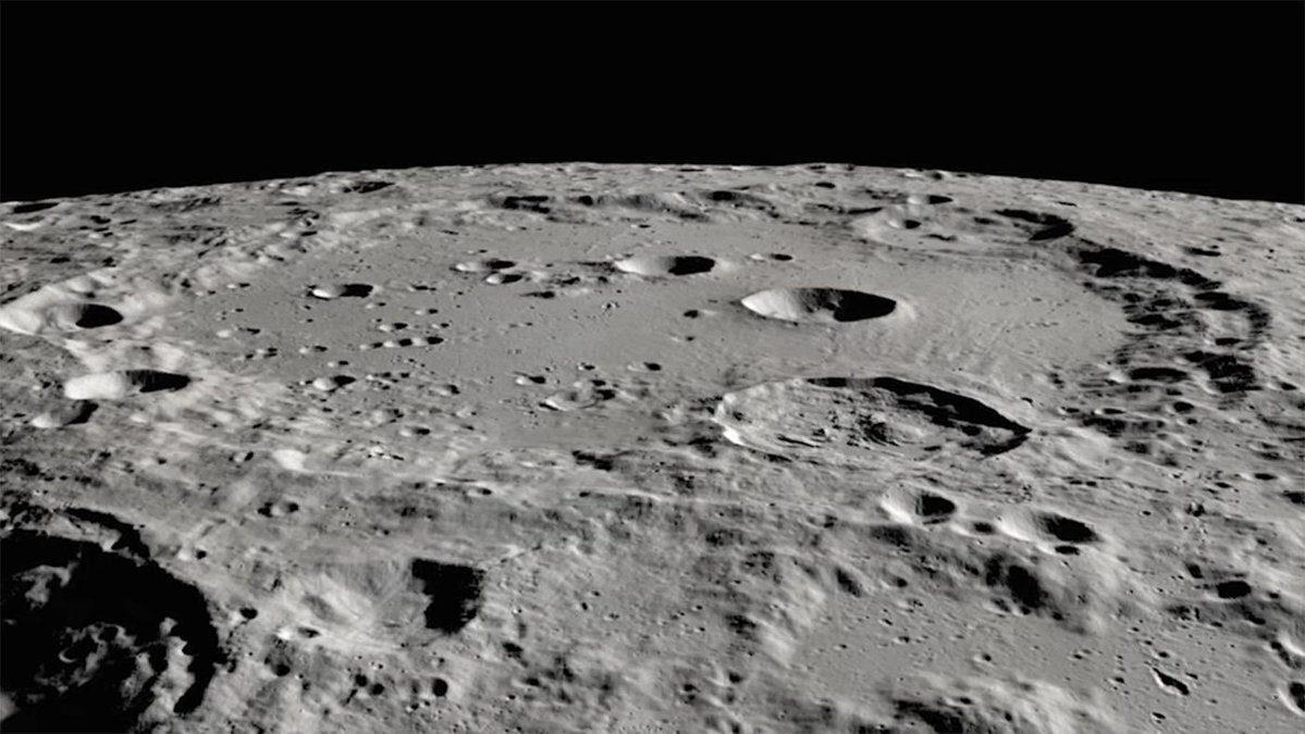 Small craters within a large crater, seen from a perspective close to the lunar surface, with the Moon's horizon in the background.