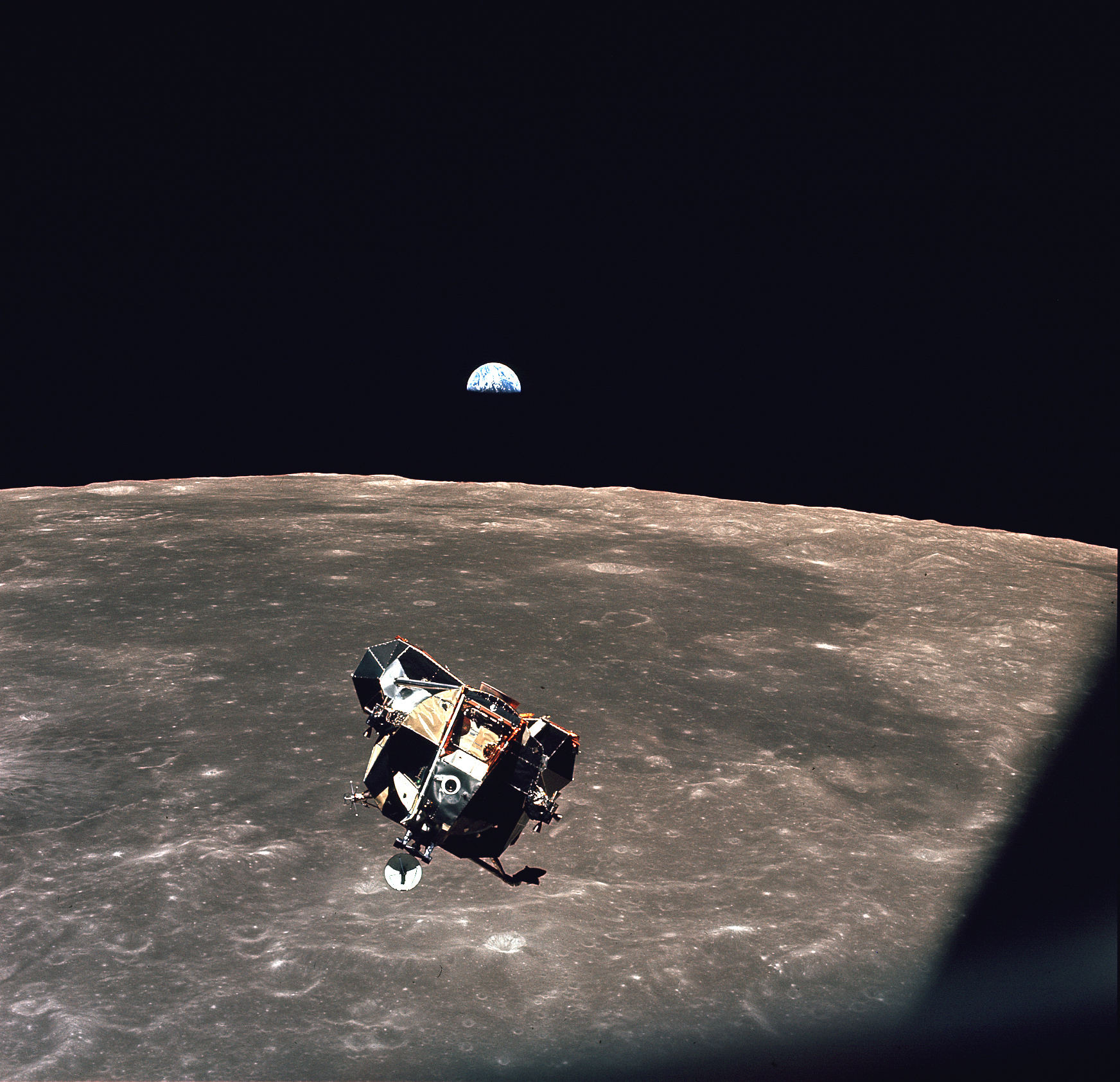 Lunar model over the Moon's rugged surface. Above the lunar horizon, Earth is brightly lit on one side.