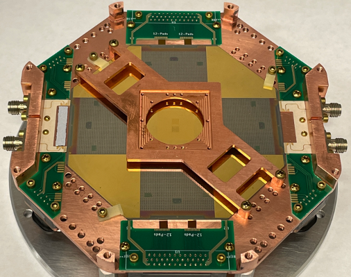 Alt tag: An octagonal shaped disc composed of copper-colored, gold-colored and silver- colored parts with 6 green circuit chip panels. The disc is mounted on a round silver metal disc.
