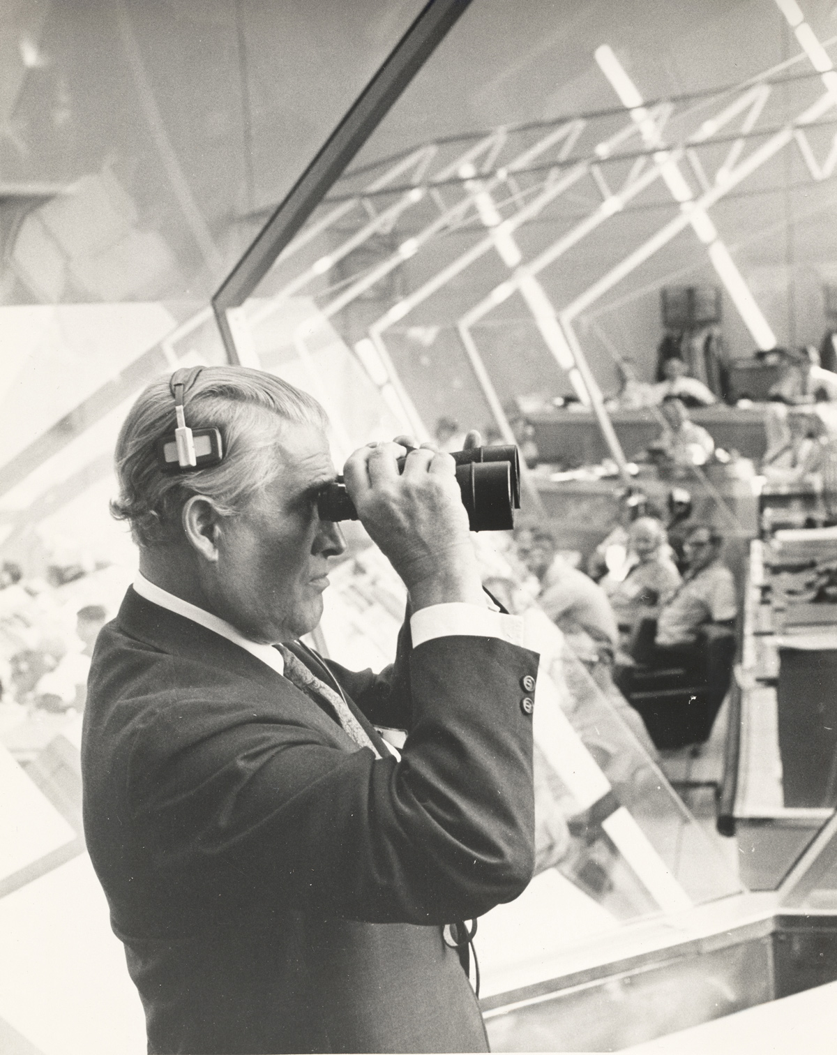 Man wearing formal suit and looking through binoculars, indoors