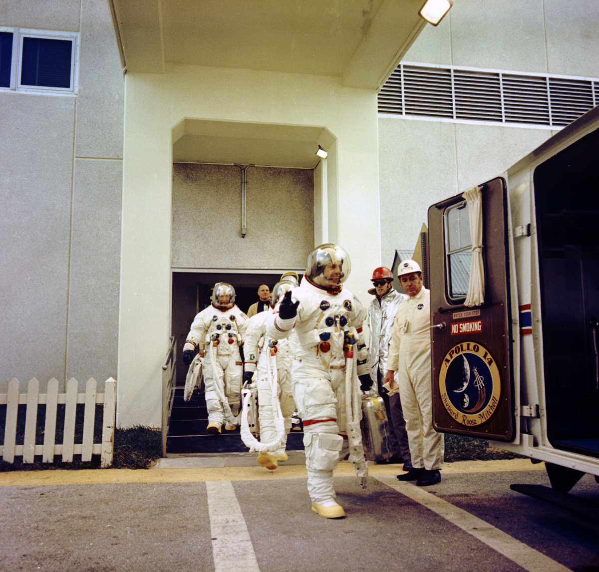 Astronaut waving while walking toward van with colleagues