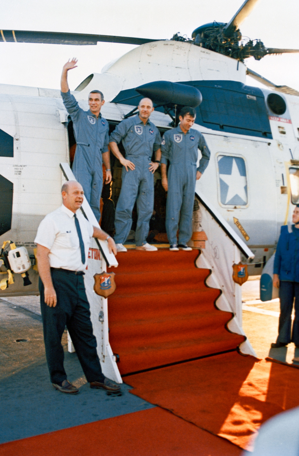 3 astronauts standing outside helicopter, on stairs covered by red carpet