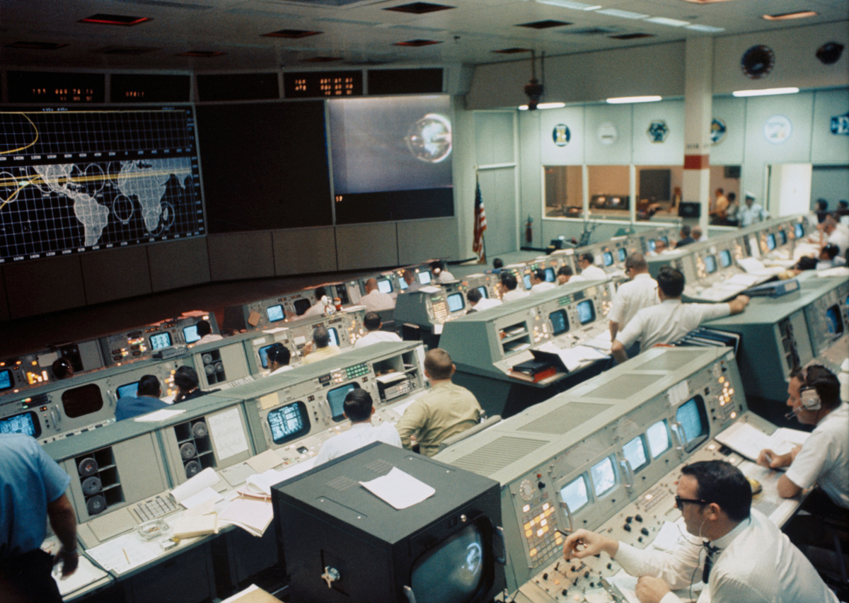 View of mission control center, with people working at rows of screens