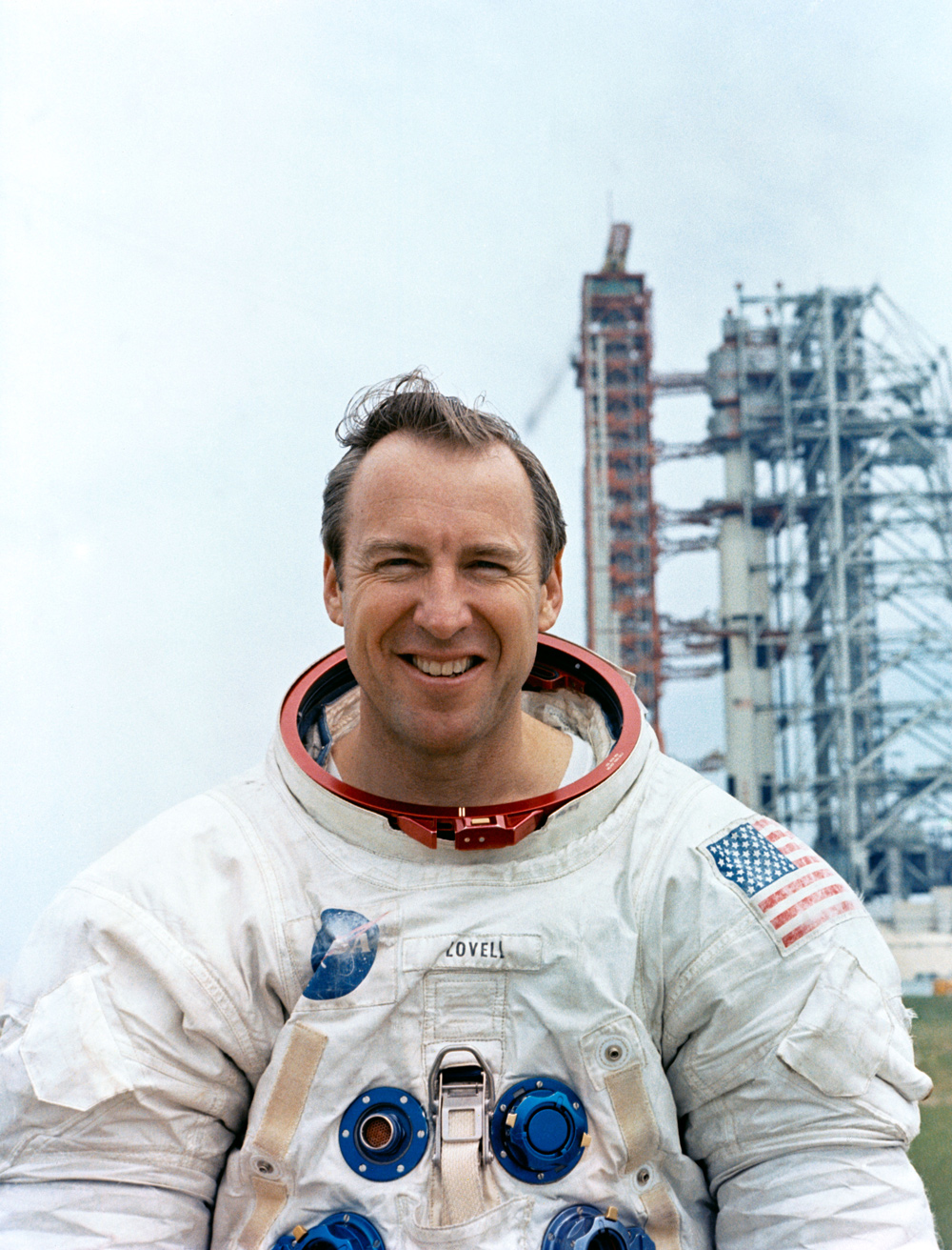 Portrait of astronaut James A. Lovell, Jr. with launch facility in background