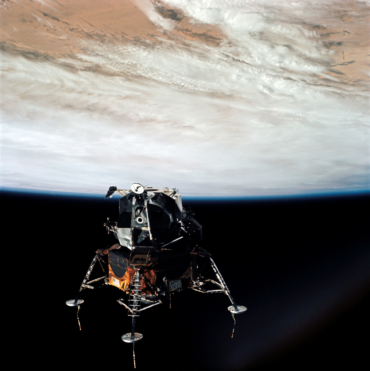 Apollo 9 Lunar Module in space with Earth, partly cloudy, in the background.