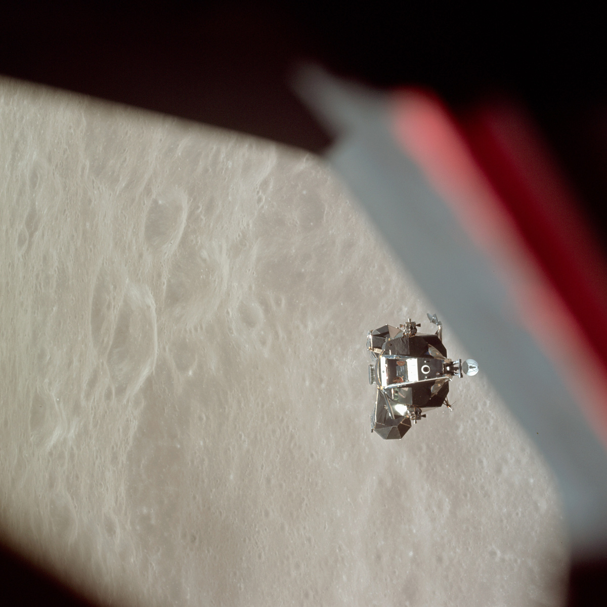 Lunar module in orbit, with the Moon's surface brightly lit in the background