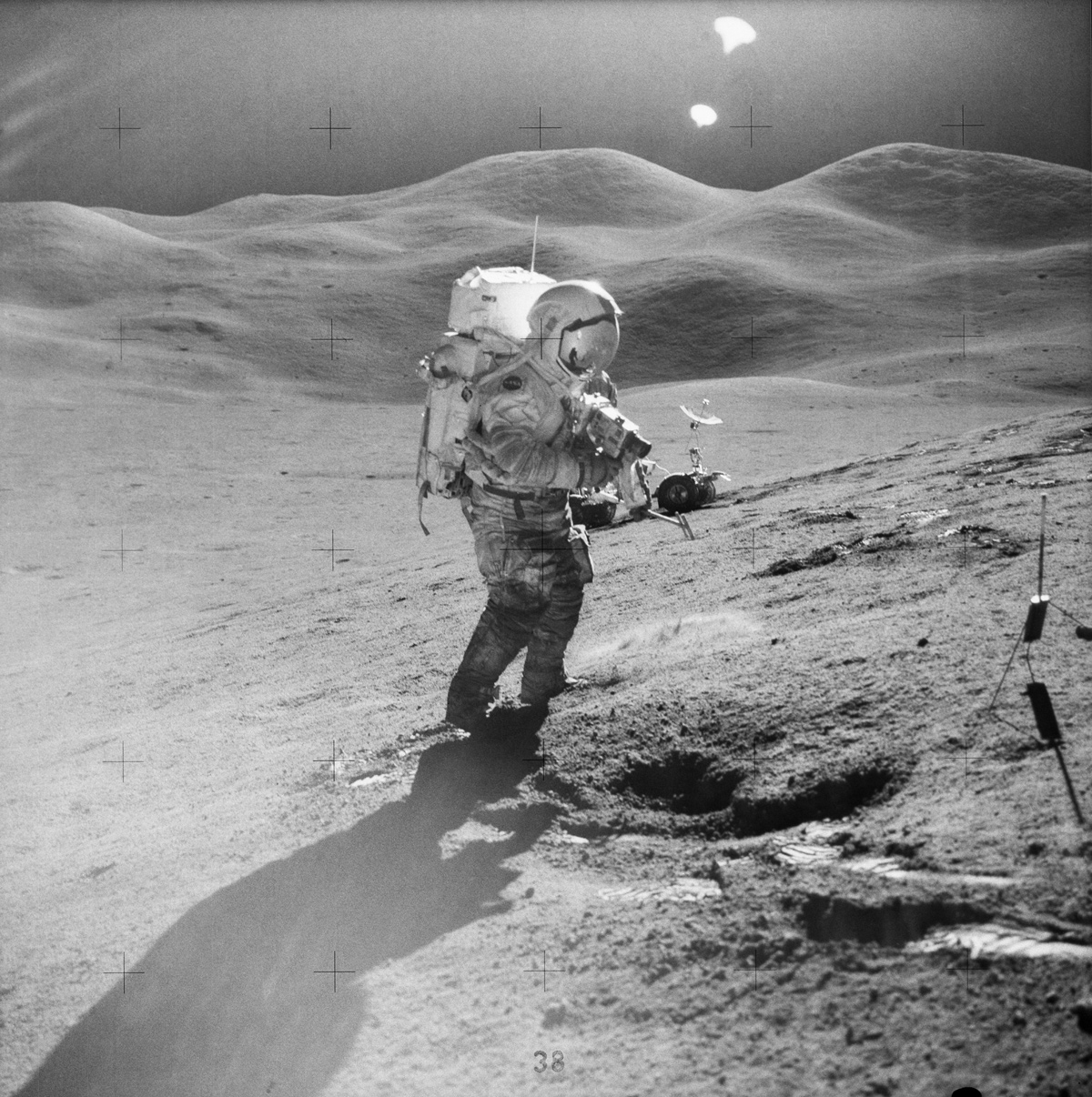 Astronaut on the lunar surface, taking a photograph. Rolling hills line the horizon in the background.