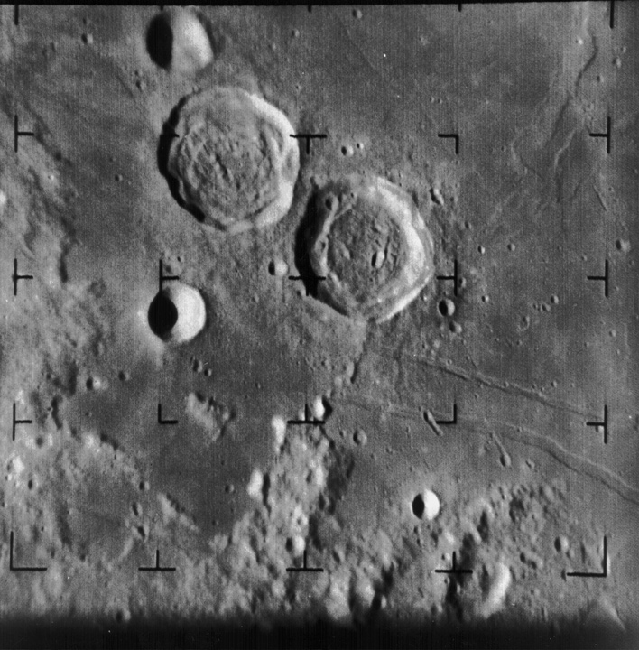 Two large, clearly defined craters on the Moon, with smaller craters and rugged terrain extending towards the bottom left. 