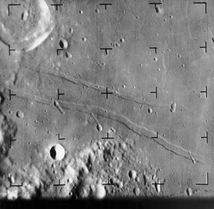 Image of the moon's surface with craters concentrated near the bottom and left edges and long ridges across the center. 