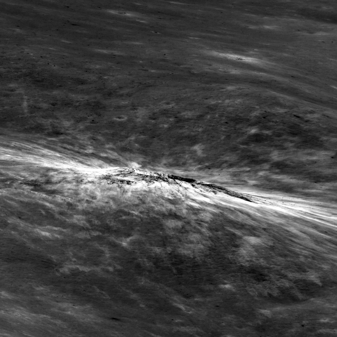 Crater seen almost edge on, on a gray, marbled-looking plain, with bright streaks extending from its rim