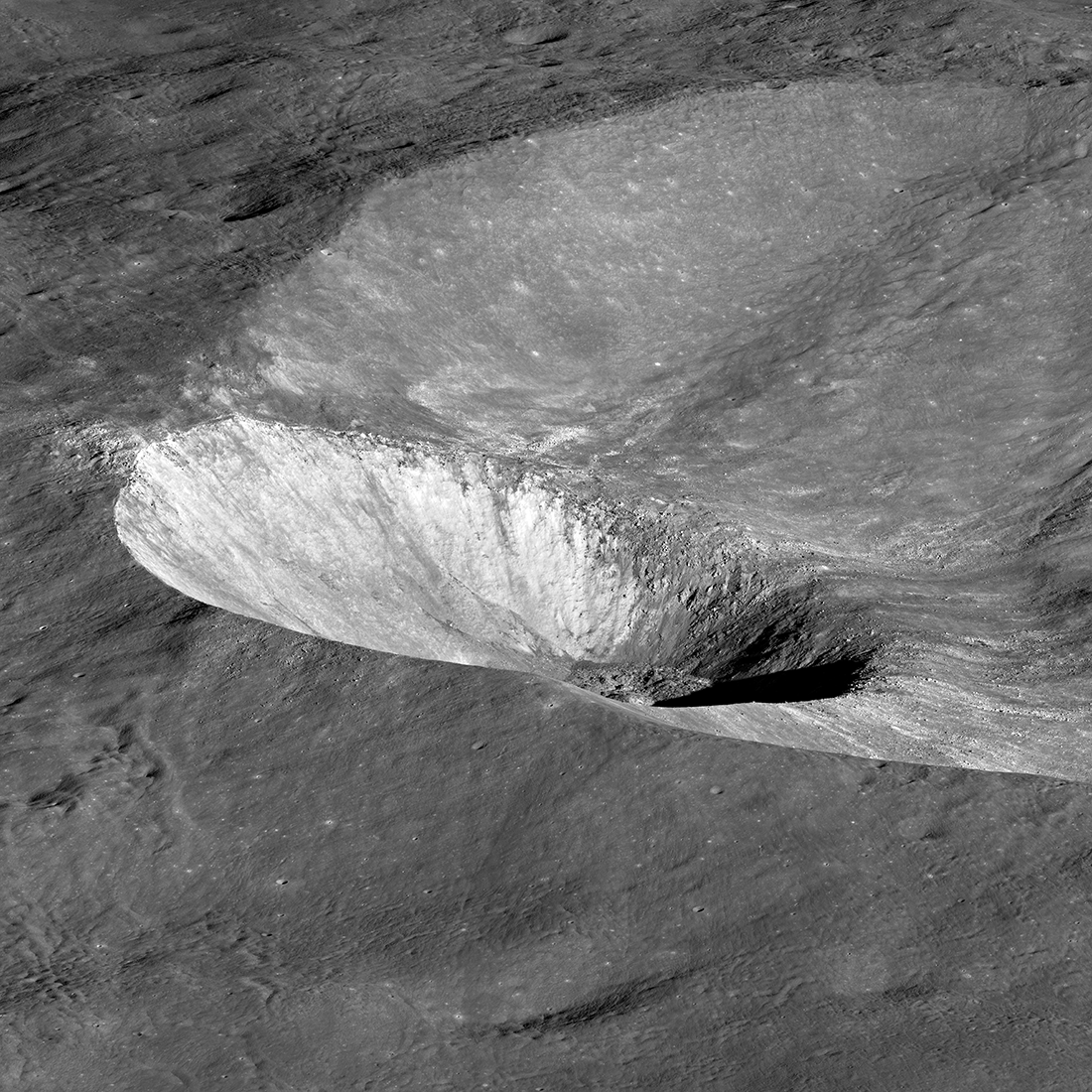 Bright, small crater crater on the sloped edge of a larger crater