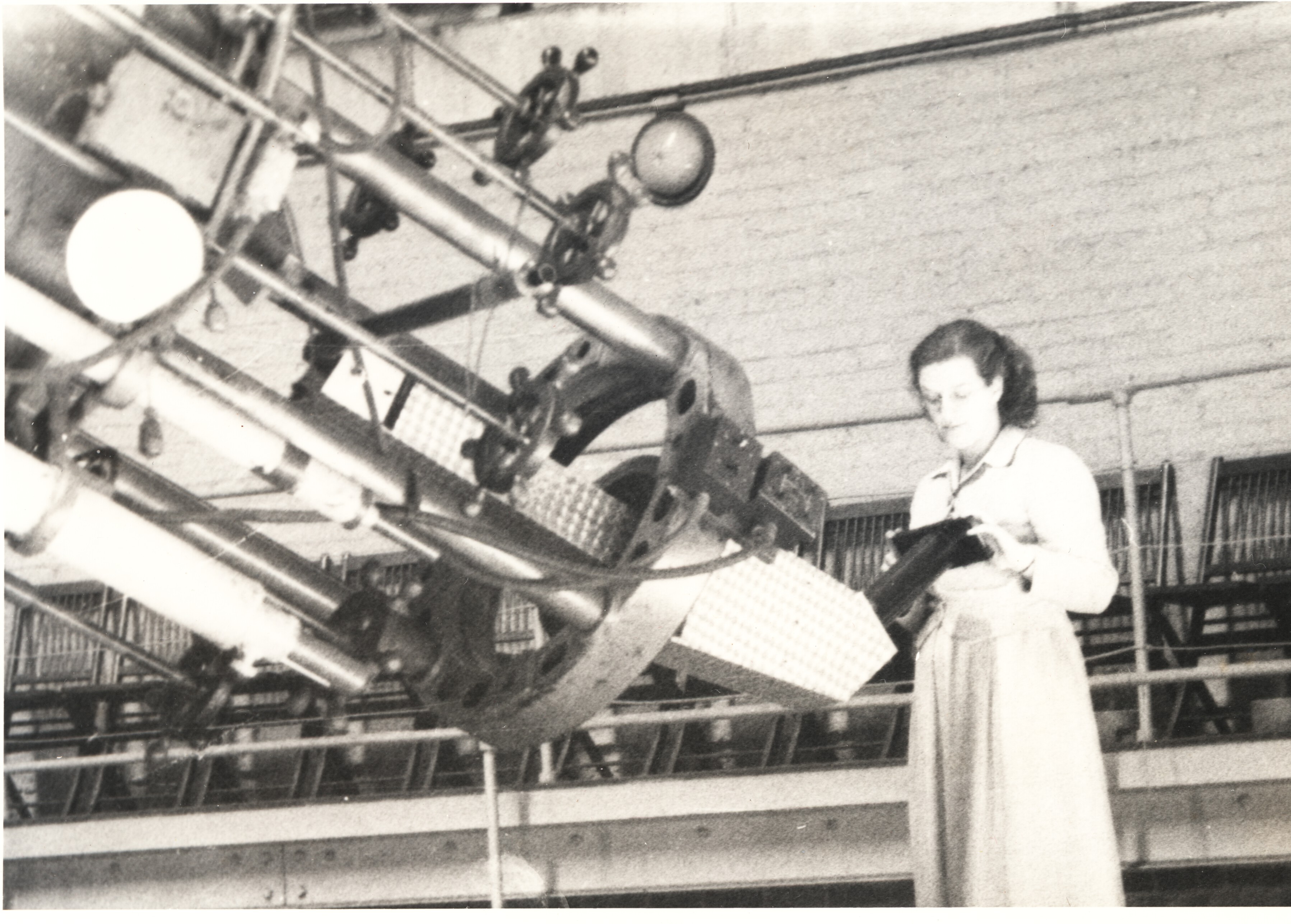 A woman stands at the end of a very large telescope in 1948