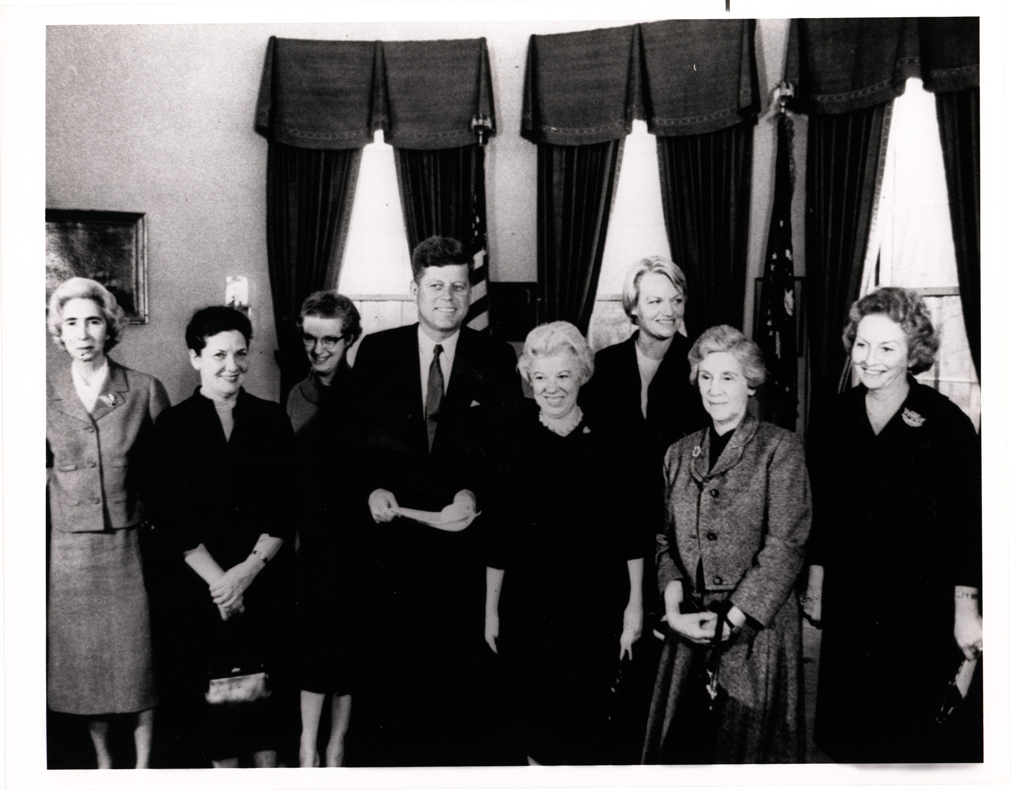 A group of women receive an award from President John F. Kennedy in the White House.