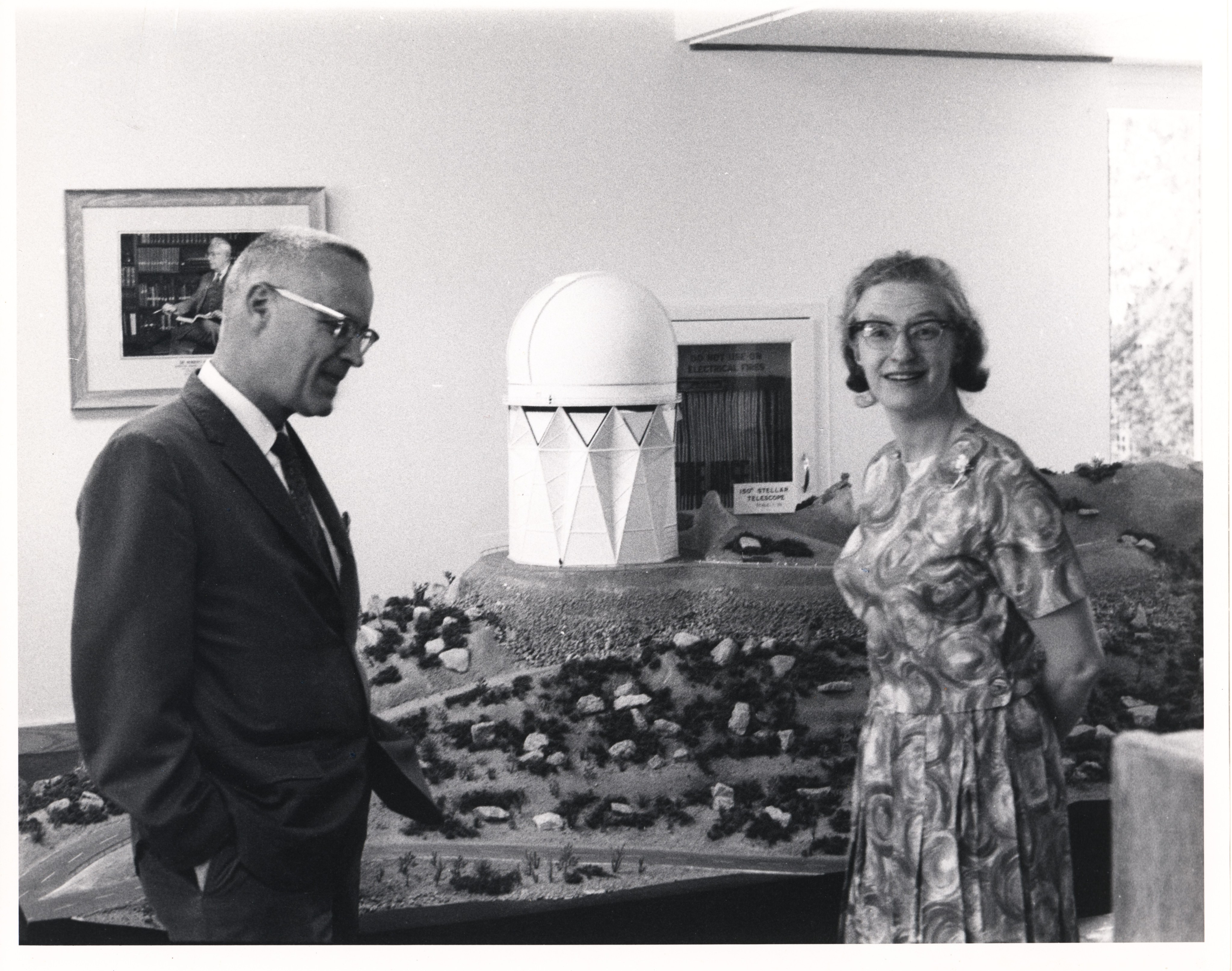 Nancy Grace Roman and NASA's Associate Adminstrator for Science and Application stand in front of a model of Kitt Peak National Observatory and talk.