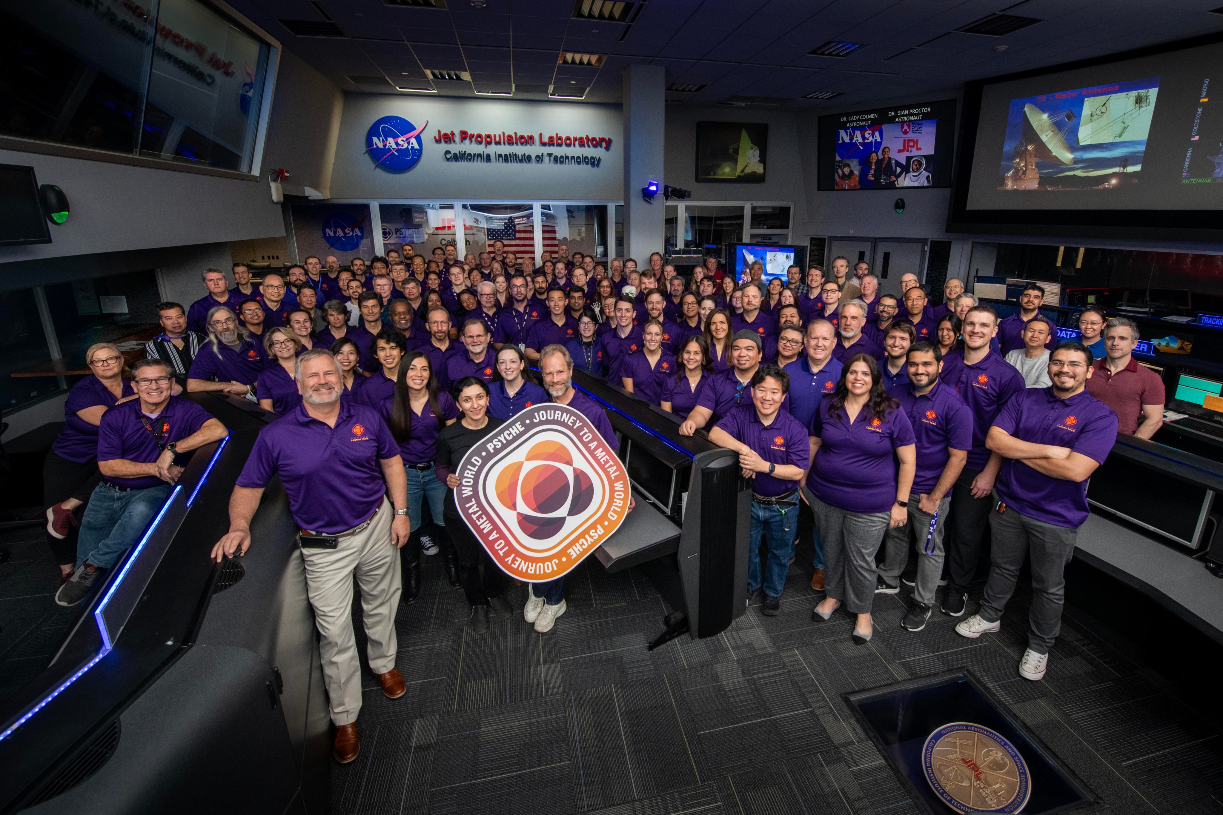 People wearing purple Psyche mission shirts pose for a photo.