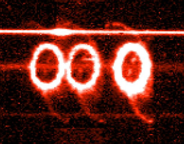 Three rings of glowing, pale red light shine in a row. The two leftmost rings are closer together.