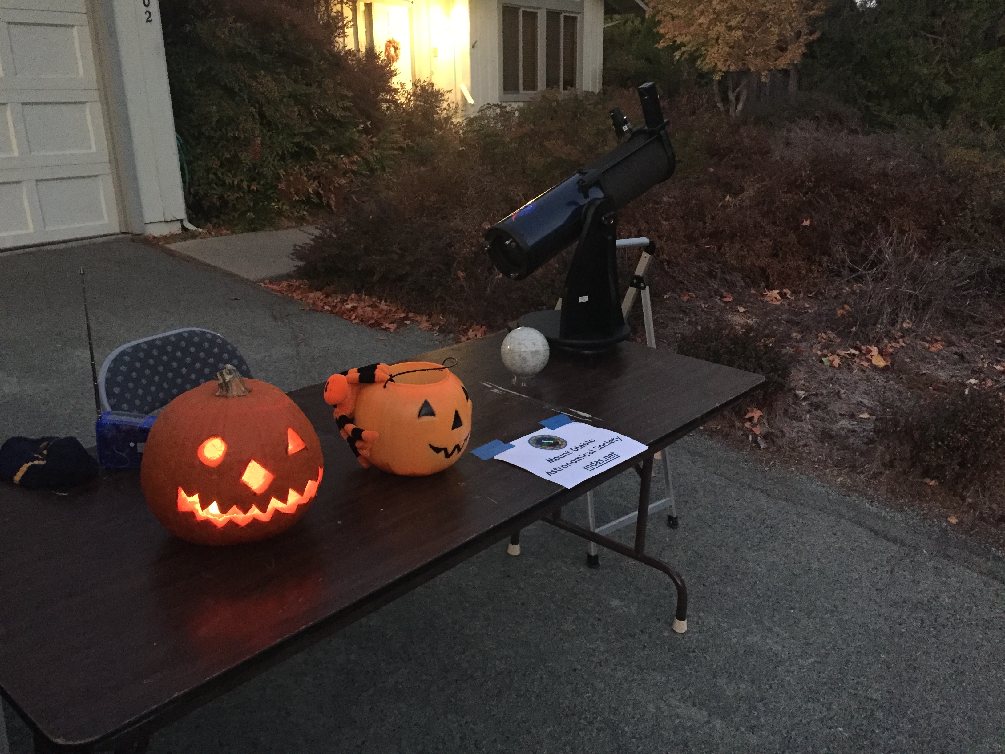 jack-o-lanterns on a table with a telescope