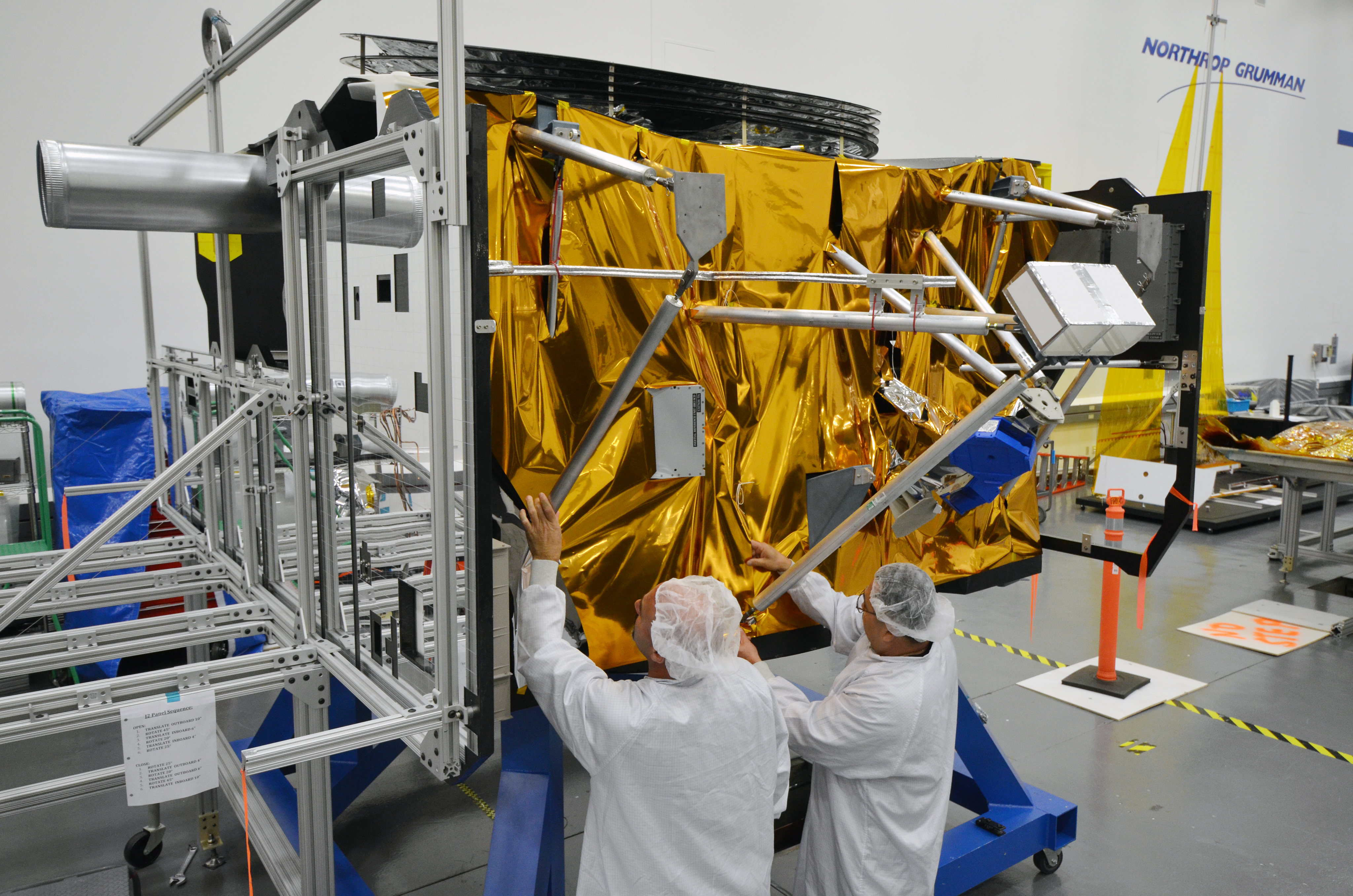 Test technicians work on a mock-up of the James Webb Space Telescope spacecraft bus