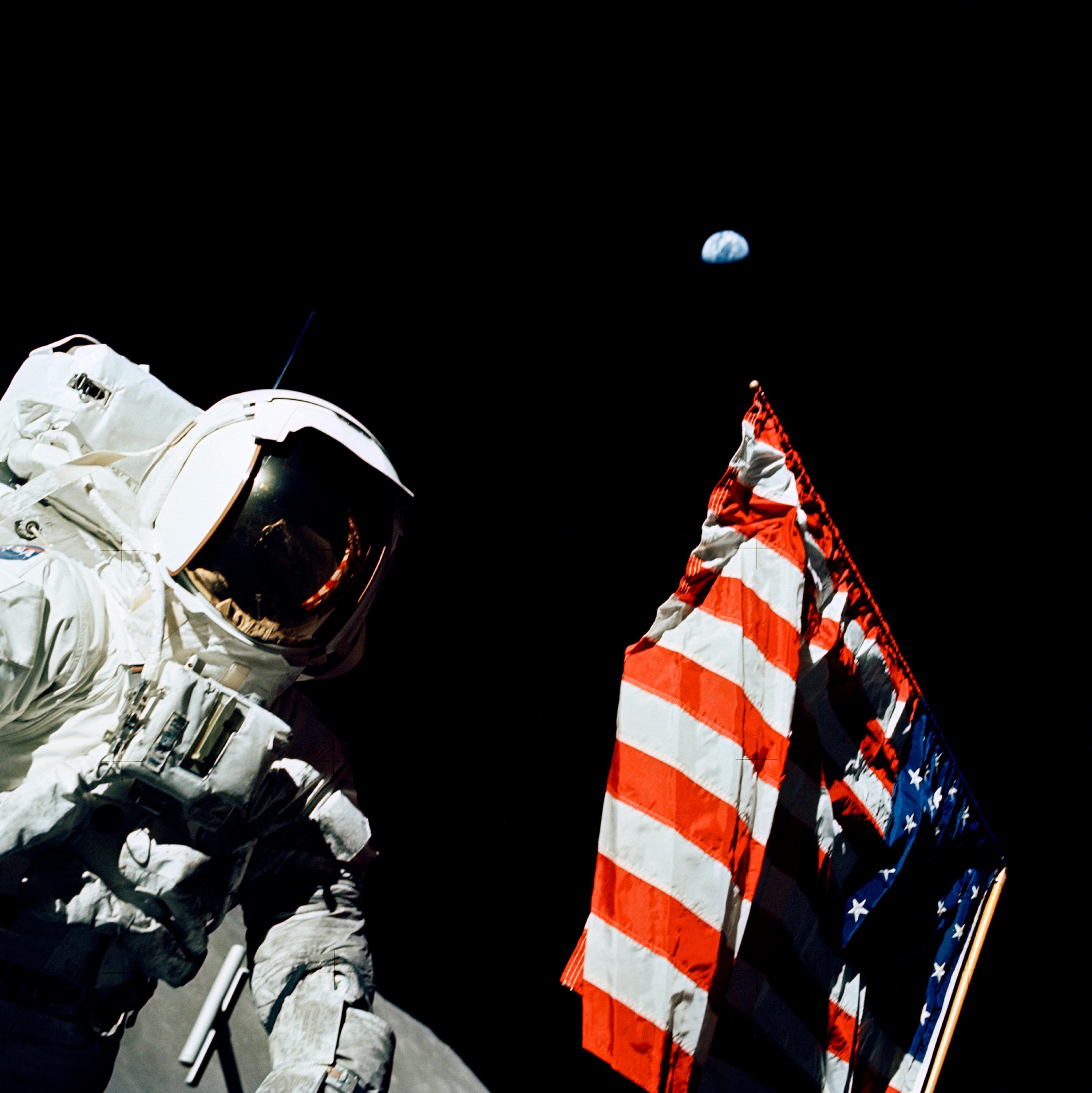 Photo of astronaut next to American flag with Earth in background