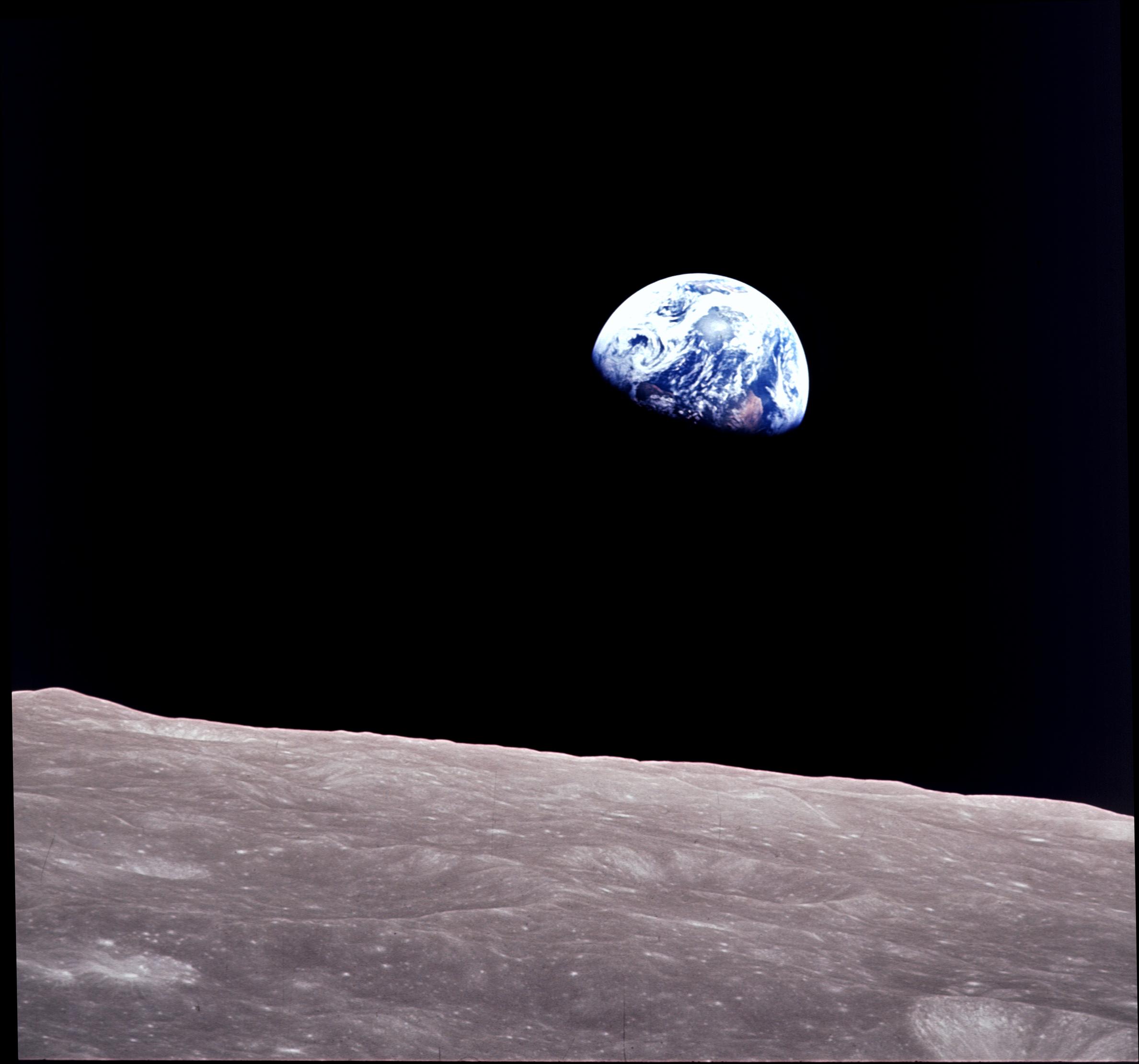 The rising Earth is about five degrees above the lunar horizon in this telephoto view taken from the Apollo 8 spacecraft.