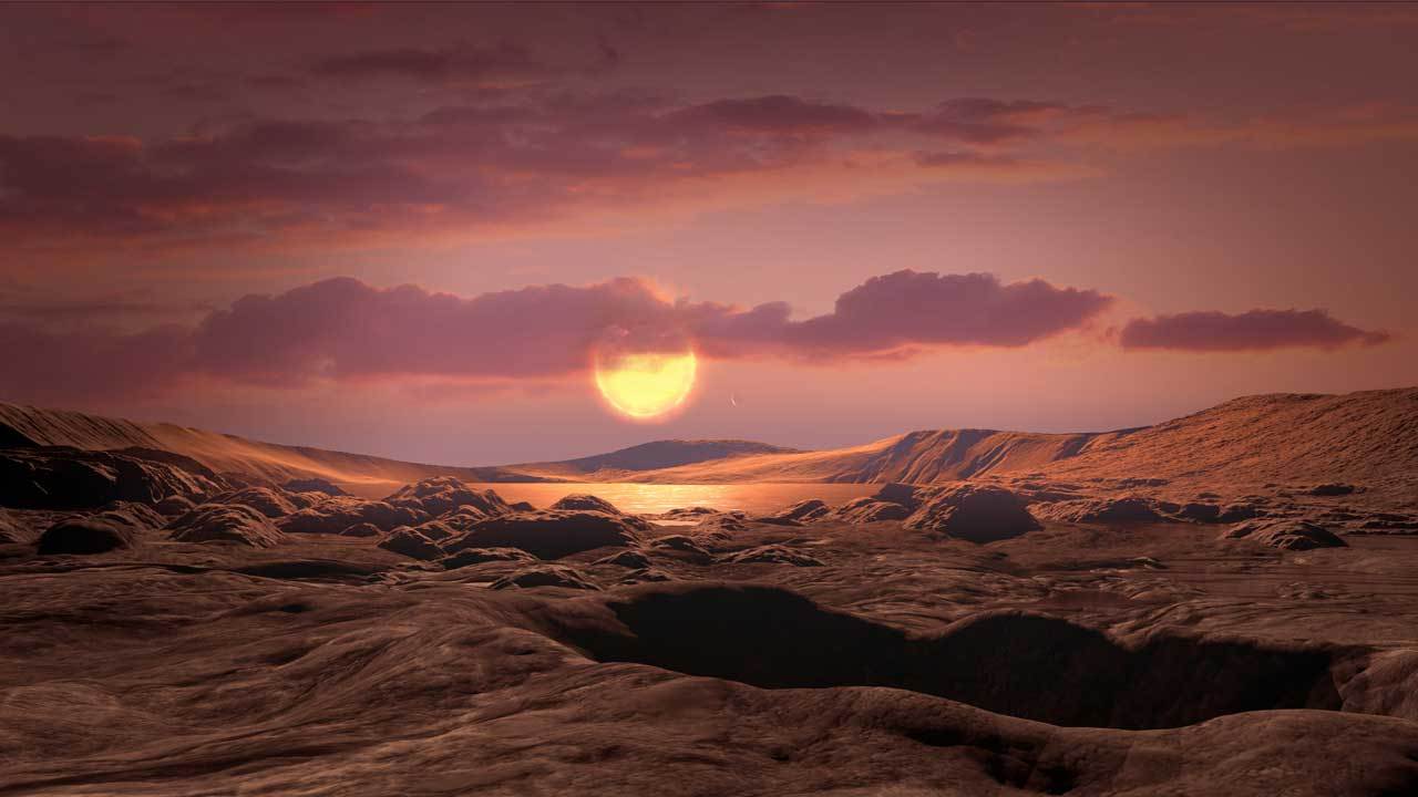 The surface of a rocky exoplanet is seen under a large star in the sky.