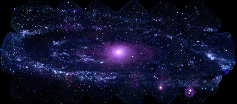 A patchy cool-blue ring of light surrounds the bright center of the M31 galaxy. The image is dotted with purple, blue and white stars.